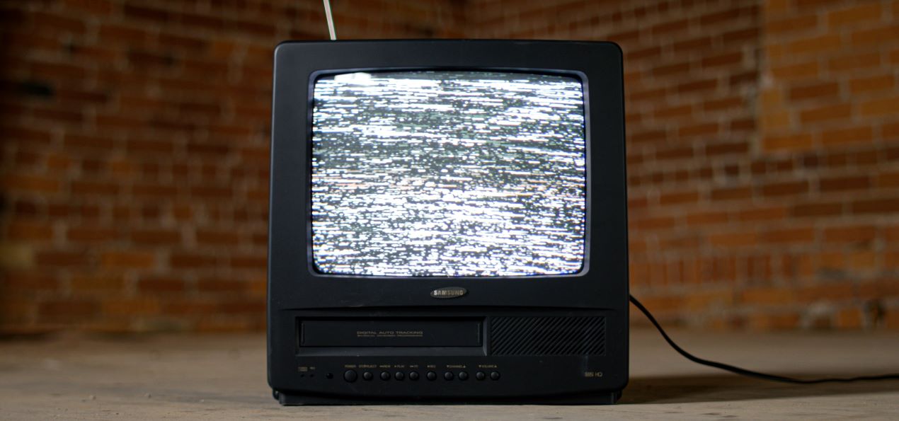 Schwarzer Röhrenfernseher mit VHS-Player und Flimmerbild – zeigt die Notwendigkeit, alte Aufnahmen durch VHS-Digitalisierung zu retten.