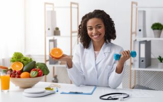 Ernährungsberaterin hält Orange und Hantel | Sportnahrung